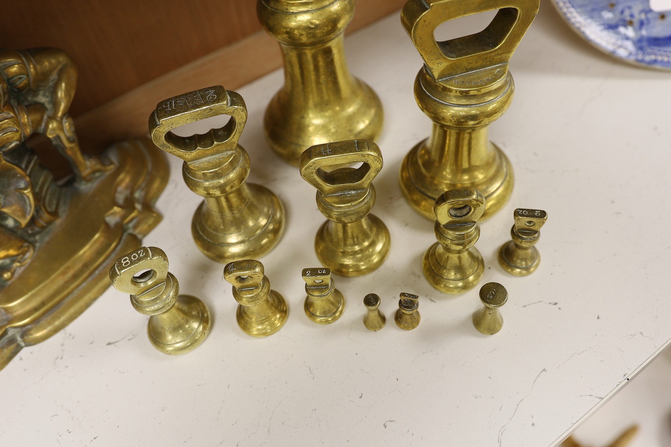 A graduated set of twelve brass bell weights and a cast brass “Punch’’ door stop. 30cm
